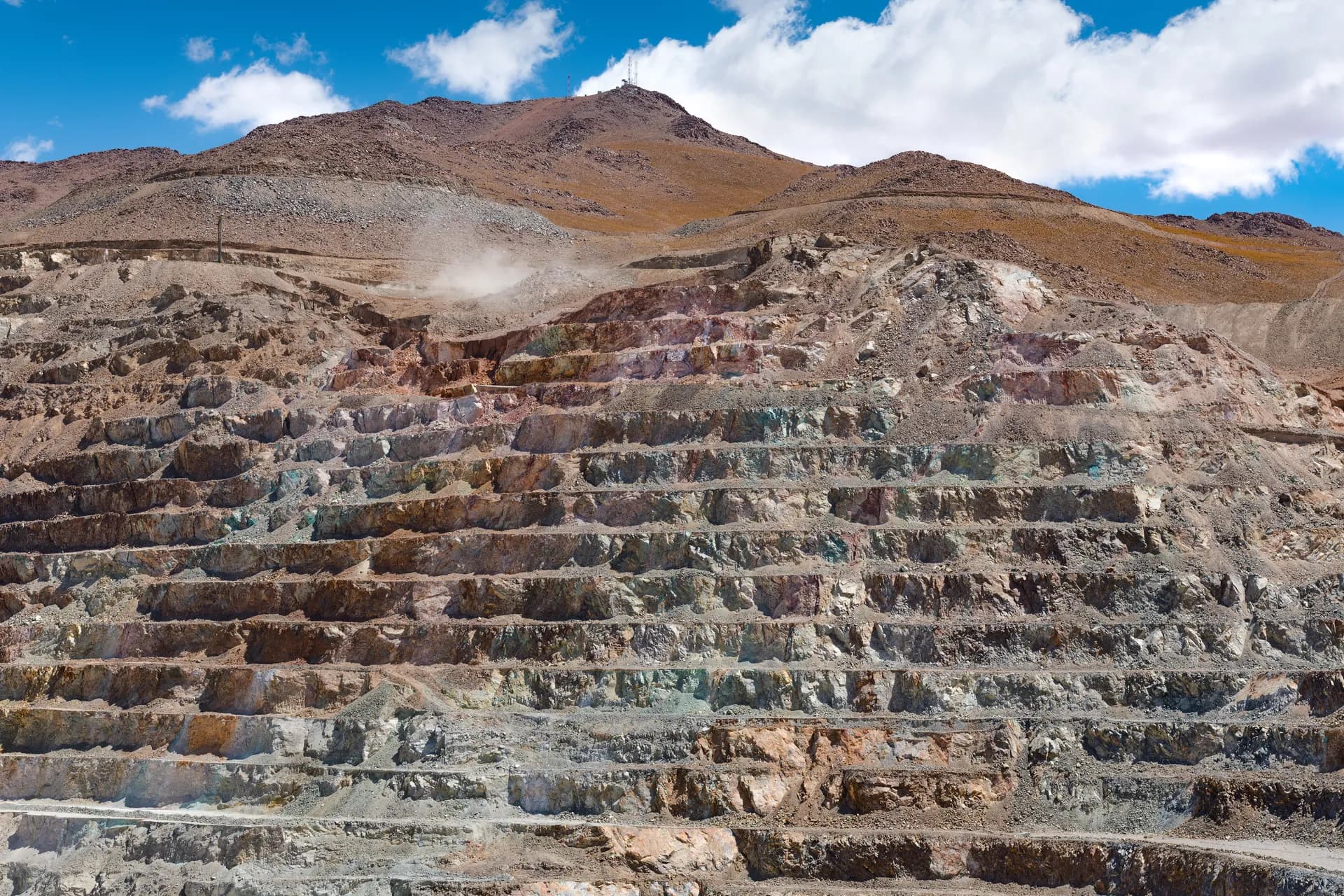 Open-pit mine with terraced benches under a clear sky